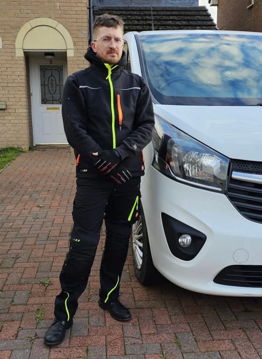 A friendly locksmith standing in front of his work van.